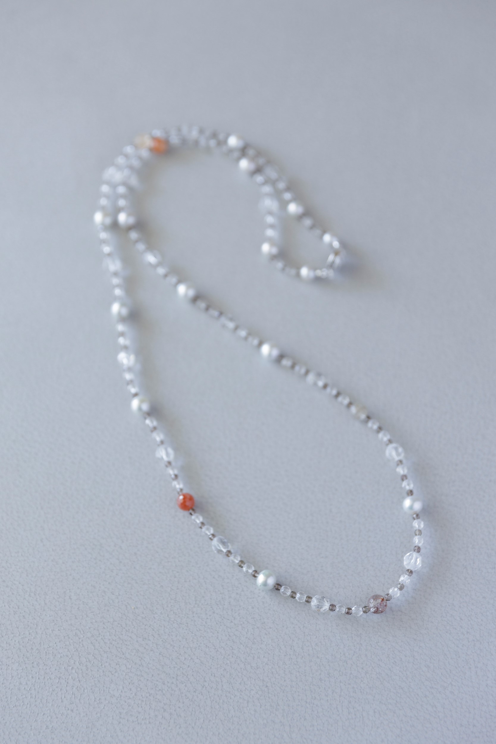 Gray pearl necklace worn with a tailored gray jacket
