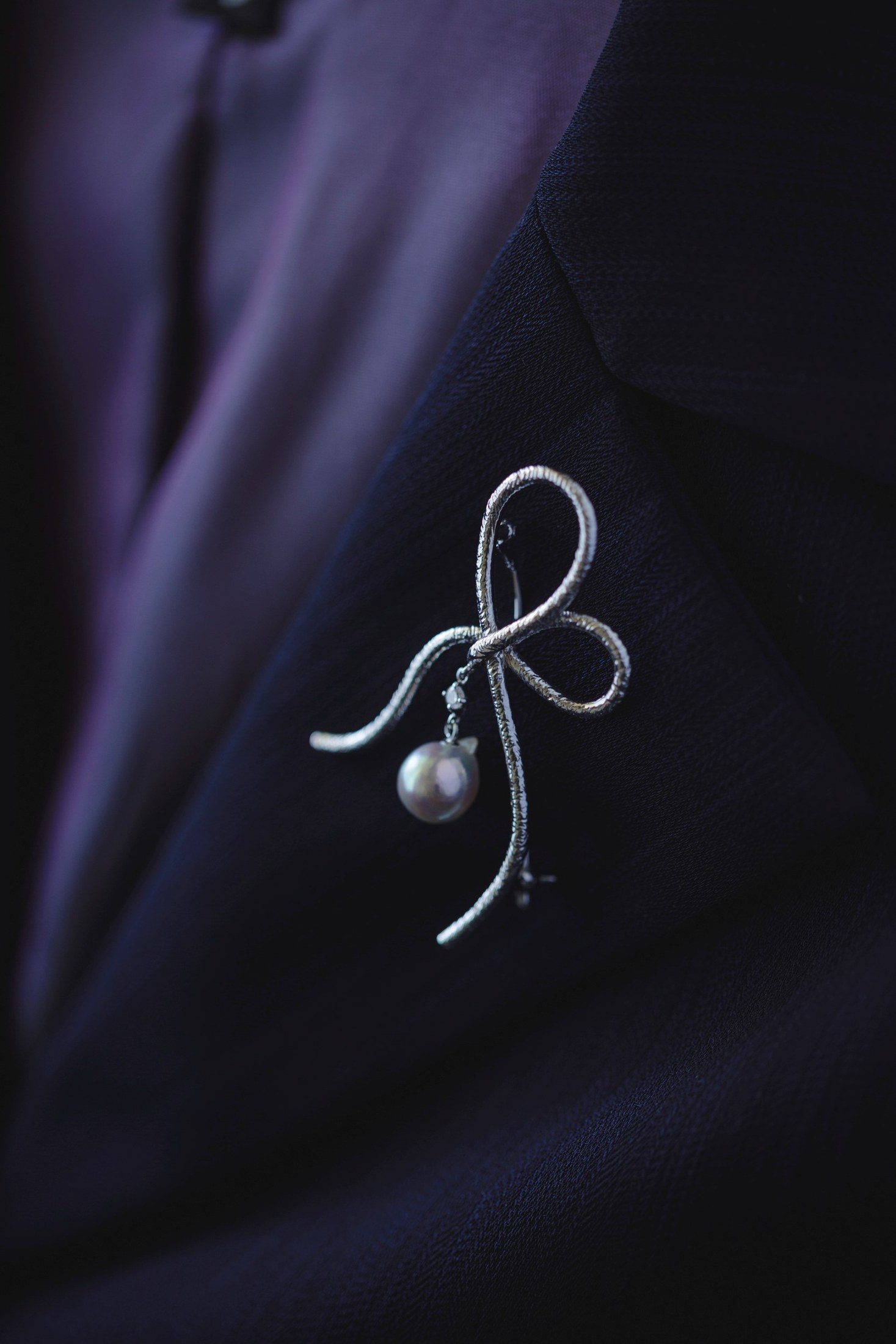 Ribbon shaped pearl brooch on dark fabric