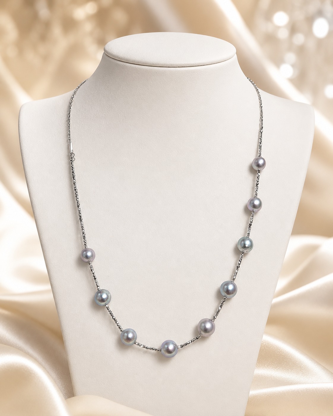 Long gray pearl necklace displayed on a white bust